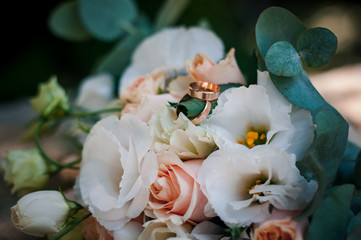 bridal bouquet of white flowers and gold wedding rings