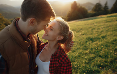 Young pretty couple hugging and smiling at the lake at sunset