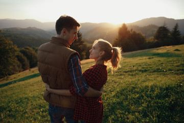 Young pretty couple hugging and smiling at the lake at sunset