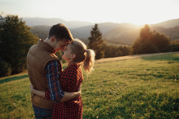 Young pretty couple hugging and smiling at the lake at sunset