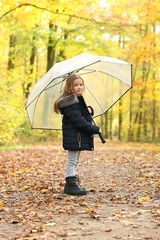 Kleines Mädchen mit Regenschirm steht in einem Wald