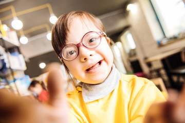 Close up of girl with Down syndrome wearing bright yellow sweater