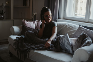 Obraz premium Girl sitting on the couch and talking on the phone