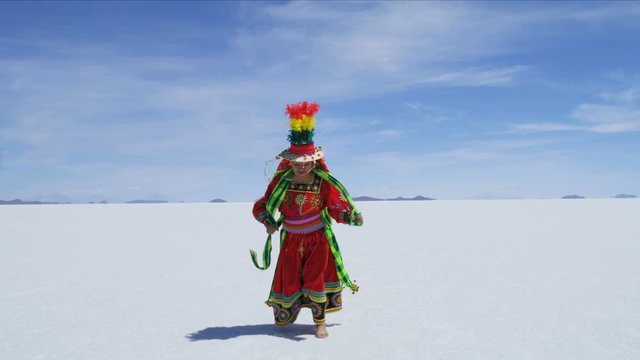 Latin American Indian woman dancing on Salar de Uyuni mineral Salt flats in traditional dress Bolivia South America 