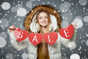 Girl in winter coat with hood on holding four hearts garland