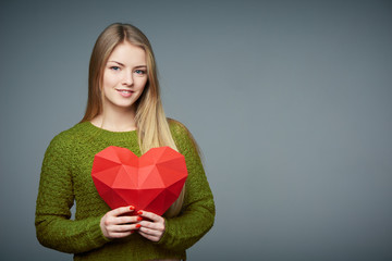 Portrait of beautiful blond girl holding heart shape