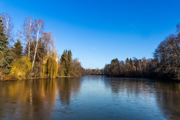 Fototapeta na wymiar Partially frozen pond in winter. End of autumn. Austria.