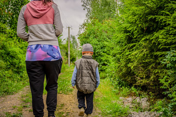 Mom and little son are walking along the road in the countryside