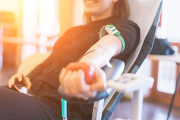 young woman as blood donor at donation with a bouncy ball holding in hand - obrazy, fototapety, plakaty