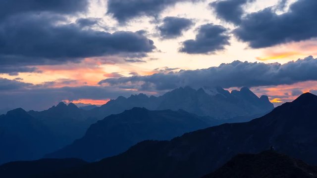 Time Lapse footage of colorful sunset in Italian Dolomites with dramatic sky scape full of clouds turning orange to black.