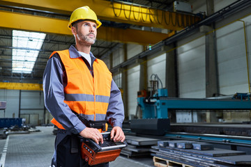 Portrait of man in factory operating machinery with remote console