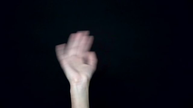 Close-up of waving hand. Waving palm of your hand signifying greeting or farewell. Black isolated background
