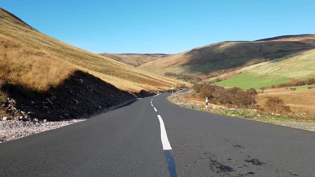jib/crane shot whilst moving forward from the centre of a road and lifting to expose more of the road and valley.