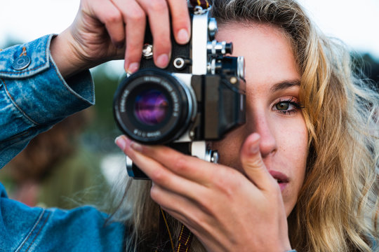 Close-up of beautiful blond young woman taking a picture with a camera