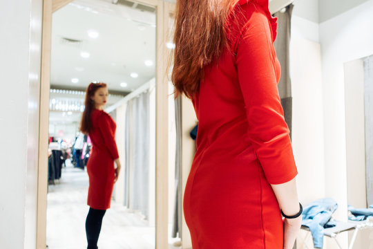 young girl tries on a red dress in a fitting room boutique. woman buys clothes in the store.