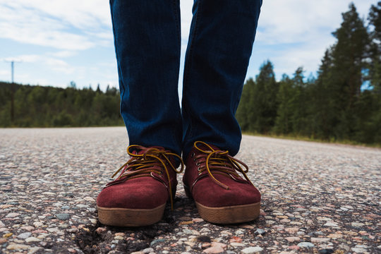 Finland, Lapland, feet of man standing on empty country road