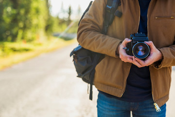 Finland, Lapland, close-up of man holding camera on country road