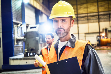 Portrait of confident man wearing protective workwear in factory