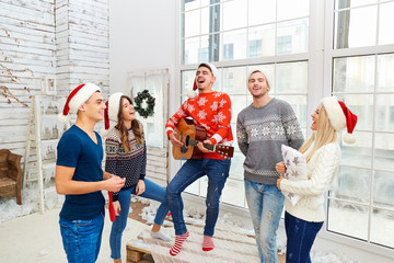 A group of friends with  guitar and singing at home on Christmas