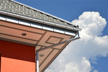 Beschichtete Dachrinne und Regenfallrohr am Dach eines modernen Verwaltungsgebäudes mit grauer...