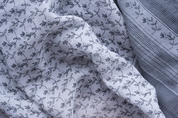 Background. An abstract pattern on fabric. Gray, silver, gloss, rhinestones. Folds, drapery, silk. Flower print.