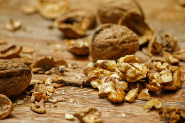 Walnuts and cracked walnuts on wooden table. Close-up, healthy food with rustic background.
