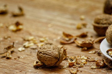 Walnuts and cracked walnuts on wooden table. Close-up, healthy food with rustic background.