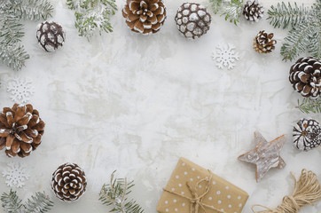 Flat lay christmas decoration composition. Frame made of fir branches, cones, gift box, wooden star, rope and snowlakes on white background with free space for lettering.