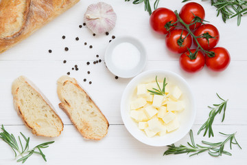 Bruschetta ingredients with mozzarella, cherry tomatoes and fresh garden rosemary. Top view with space for your text