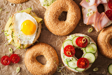 variety of sandwiches on bagels: egg, avocado, ham, tomato, soft cheese, alfalfa sprouts