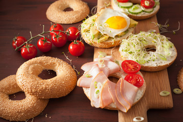 variety of sandwiches on bagels: egg, avocado, ham, tomato, soft cheese, alfalfa sprouts