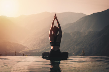 Mooie aantrekkelijke Aziatische vrouw beoefent yoga Lotus pose op het zwembad boven de bergtop in de ochtend voor een prachtig uitzicht op de natuur, voel je zo comfortabel en ontspan in vakantie, warme toon