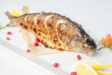 Baked fish on a plate on a white background