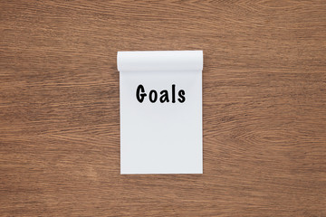  top view of notebook with 'goals' lettering on wooden background