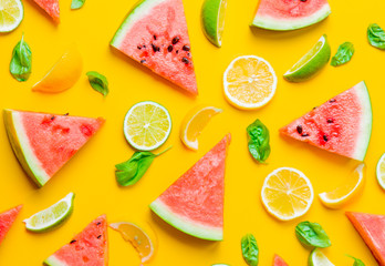 Above view at cutted lemons and limes with watermelon on yellow background