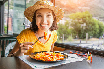 Happy smiling woman in eating pasta in restaurant