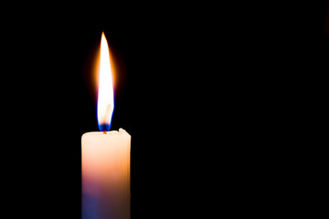 A  candle burns brightly on a black, isolated background. Free space for text_