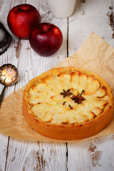 Traditional holiday apple pie. Baked dessert with anise, cloves and apples on light wooden background