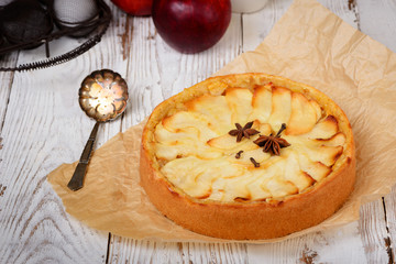 Traditional holiday apple pie. Baked dessert with anise, cloves and apples on light wooden...