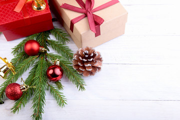 Christmas tree and cones, New Year's colorful balls with ribbon and gift box on white wood background. Decoration for happy holidays. Copy space. Top view.