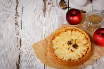 Traditional holiday apple pie. Baked dessert with anise, cloves and apples on light wooden...