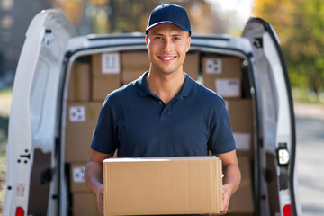 Delivery man standing in front of his van - obrazy, fototapety, plakaty