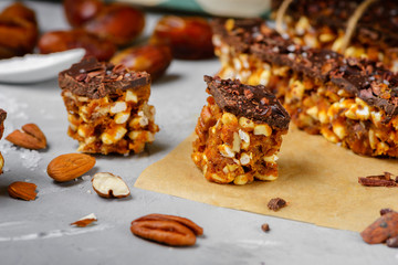 Raw vegan energy bars with dates and nuts and chocolate frosting. Homemade healthy snack sweets.