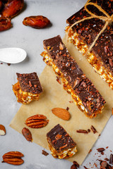 Raw vegan energy bars with dates and nuts and chocolate frosting. Homemade healthy snack sweets.