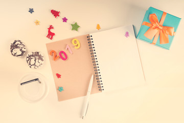2019 Goal. Notebook, pen, decorations, gift, coffee and cookies on white desk. New year resolution. Christmas wish list. New Year plan. Colorful number 2019 and party decorations. Copy space. Toned