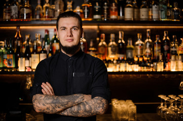 Tattooed bartender standing on the background of the bar