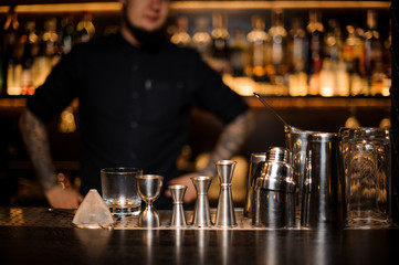 Bartender standing on the bar on the foreground of equipment
