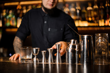 Professional bartender standing on the bar on the foreground of equipment