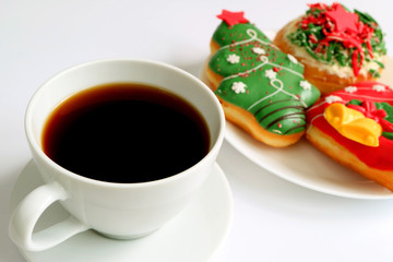 Cup of Coffee with a Plate of Christmas Decorated Sweets in Background 