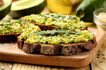 Avocado and arugula sandwiches closeup on natural wooden table. Sandwich with avocado puree.